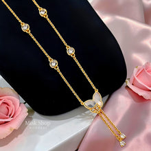 Close-up of a long 18K gold plated butterfly necklace with natural mother-of-pearl wings, zircon stations, and two delicate drop chains by Misk Shop.