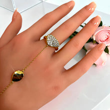Close-up of free-size pavé zircon ring connected to a gold hand chain