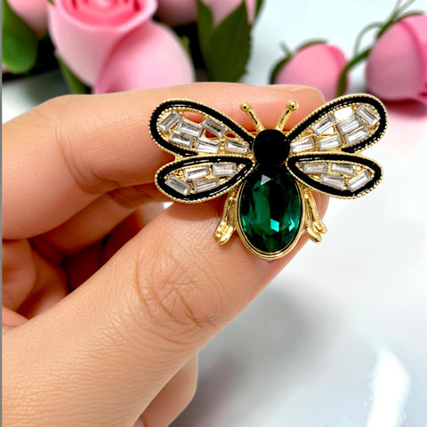 Handcrafted 21K gold color bee brooch with baguette zircon wings, black enamel details and emerald green crystal by Misk Shop.