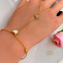 Close-up of a mother-of-pearl heart framed with zircon on a gold hand chain