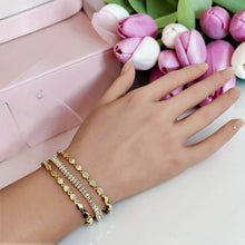 Triple-row connected gold bracelet with baguette-style zircon center and oval gold beads worn on wrist