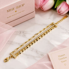Connected 3-in-1 gold bracelet with paperclip links, clear zircon row and faceted gold beads, laid flat