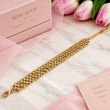 Wide 18K gold-plated woven shawl bracelet with interlocking gold links, clasp and adjustable extension laid flat