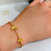 Close-up of LV initials and polished four-petal flowers on a gold-plated bracelet
