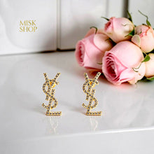 Close-up of gold plated interlocking YSL letter earrings with clear sparkling accents