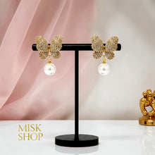 Pair of 18K yellow gold plated butterfly and cultured pearl drop earrings on a display stand