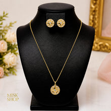 Compass star necklace and matching round earrings in 21K yellow gold plating on a black display