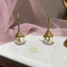 Close-up of gold plated cultured pearl earrings with zircon petal-shaped caps