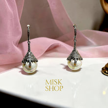 Close-up of white gold plated cultured pearl earrings with zircon petal-shaped caps