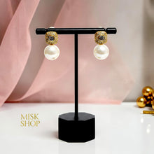 Pair of 18K gold plated cultured pearl and rounded-square zircon earrings on a display stand