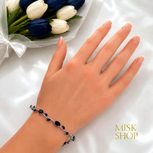 Close-up of silver-tone navy zircon tulip bracelet styled on the wrist