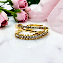 Close-up of a gold open crossover ring with clear stone bands