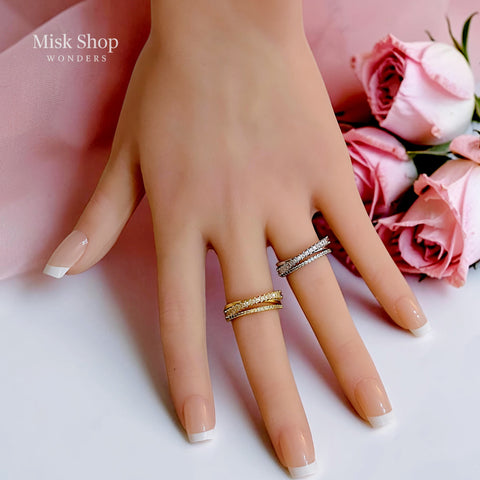 Gold and silver open crossover rings with clear stone detailing worn on a hand