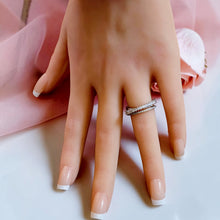Silver open crossover ring with clear stone detailing worn on a hand
