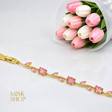 Close-up of gold-tone bracelet with round and leaf-cut pink zircon stones