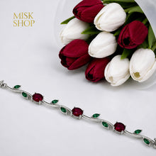 Close-up of silver-tone bracelet with round red and leaf-cut green zircon stones