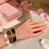Reversible LV-inspired leather bracelets in dark brown, camel brown, and white worn on wrist