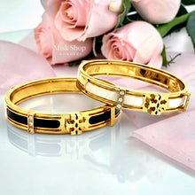 Close-up of Misk Shop Tory Burch inspired enamel bangles in ivory white and black with 18K gold plating