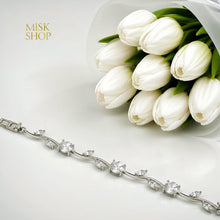 Close-up of gold-tone bracelet with round and leaf-cut clear zircon stones