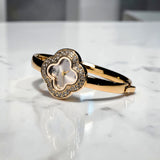 Close-up of XIMILI gold flower bangle watch with ivory dial and zircon frame by Misk Shop.